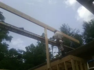 Carpenter setting a ridge beam over a new addition frame — Ice Dam Removal by Roofing Brothers in Perry